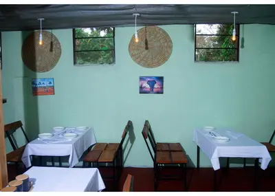 a dining room with white tables and chairs and windows at Ngorongoro Villa and Restaurant in Karatu