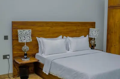 a bedroom with a white bed with a wooden headboard at Tulivu Kilimanjaro Retreat in Moshi