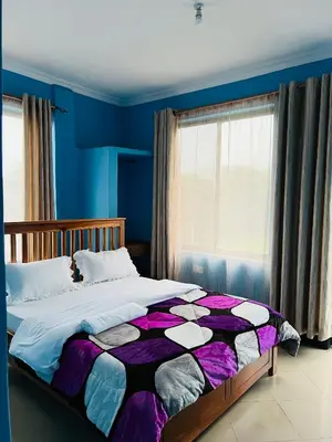 a bedroom with a large bed with blue walls at Kilimanjaro Smiley Inn in Moshi
