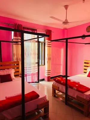 two beds in a room with pink walls at Kilimanjaro Smiley Inn in Moshi