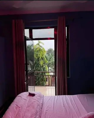 a bedroom with a bed and a window with a balcony at Kilimanjaro Smiley Inn in Moshi
