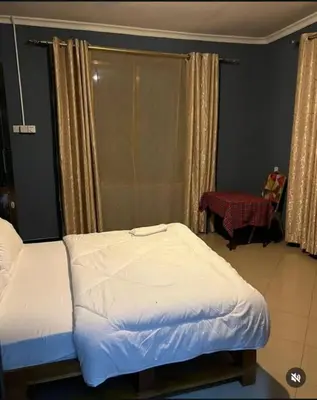 a small bedroom with two beds and a chair at Kilimanjaro Smiley Inn in Moshi