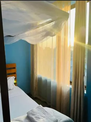 a bedroom with two beds and a window at Kilimanjaro Smiley Inn in Moshi