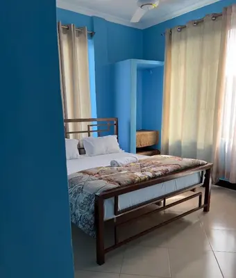 a bedroom with a bed with blue walls at Kilimanjaro Smiley Inn in Moshi