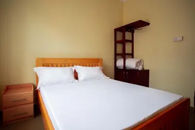 a bedroom with a large white bed and a shelf at BCB Homes in Moshi