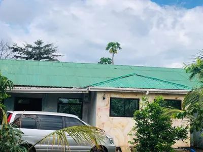 a car parked in front of a house with a green roof at Kilibase Hotel in Moshi