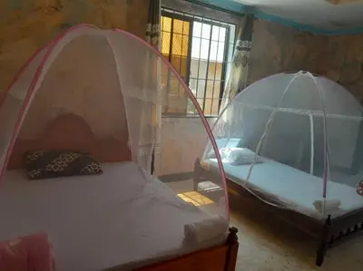 two beds in a room with a canopy at Kilibase Hotel in Moshi