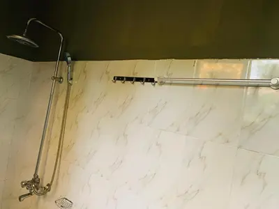 a shower in a bathroom with a white marble wall at Kilibase Hotel in Moshi