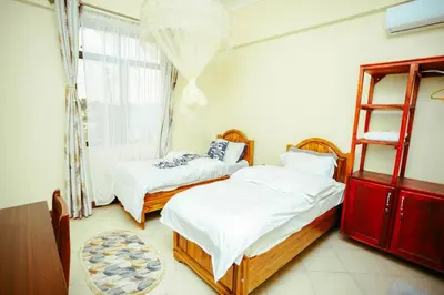 two beds in a room with a window at CM Luxury Lodge in Moshi