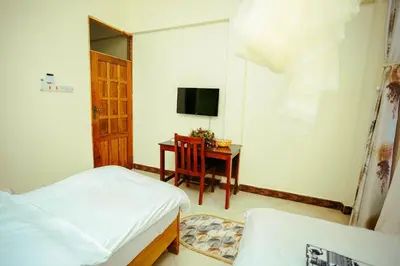 a bedroom with a bed and a table with a television at CM Luxury Lodge in Moshi