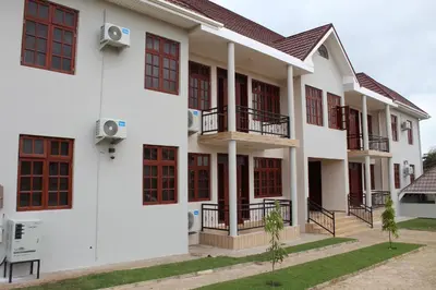 an exterior view of a white building with red windows at NAURA HOMESTAYS in Arusha