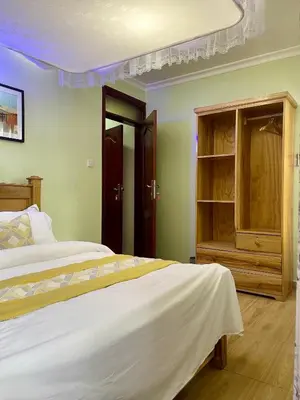 a bedroom with a bed and a wooden cabinet at NAURA HOMESTAYS in Arusha