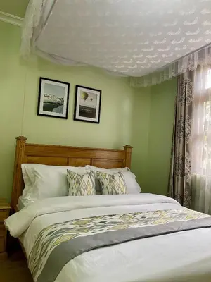 a bedroom with a bed and two pictures on the wall at NAURA HOMESTAYS in Arusha