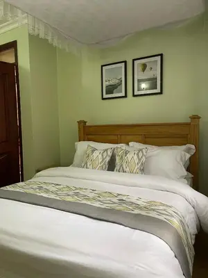 a bed in a bedroom with two pictures on the wall at NAURA HOMESTAYS in Arusha