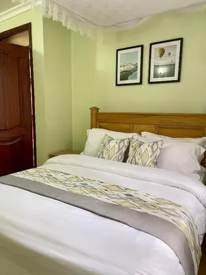 a bed with white sheets and pillows in a room at NAURA HOMESTAYS in Arusha