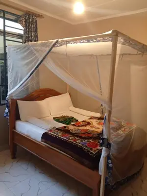 a bed with a canopy in a room at The Secret Garden Hotel Moshi in Moshi
