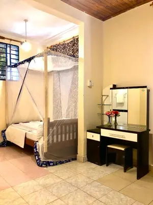 a bedroom with a bed and a desk and a mirror at The Secret Garden Hotel Moshi in Moshi