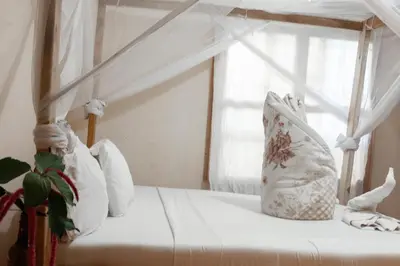 a white bed with white pillows and a window at The Secret Garden Hotel Moshi in Moshi