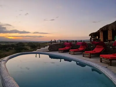 a swimming pool with chairs and a sunset in the background at Original Maasai Lodge – Africa Amini Life in Ngare Nanyuki