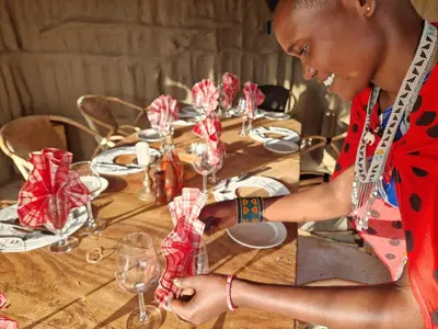 a woman sitting at a table set with wine glasses at Original Maasai Lodge – Africa Amini Life in Ngare Nanyuki