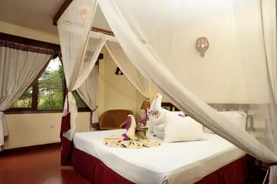 a bedroom with a bed with white sheets and pillows at Kia Lodge in Arusha