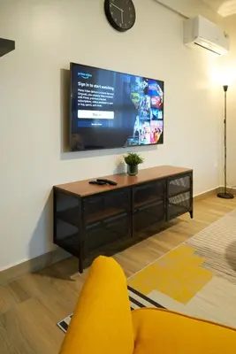 a living room with a tv and a yellow chair at Westwood Residences in Arusha