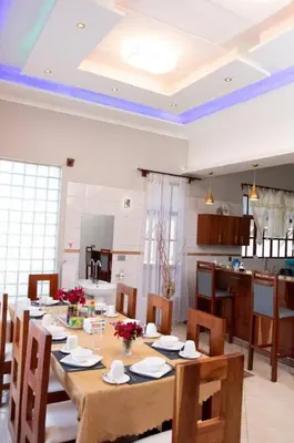 a dining room with a table and a kitchen at Simba Villa in Arusha