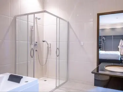 a bathroom with a shower and a sink and a mirror at Sanna Boutique Hotel in Arusha