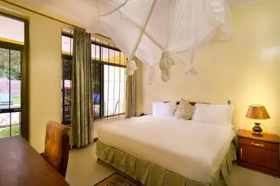 a bedroom with a white bed with a window at Mvuli Hotels Arusha in Arusha