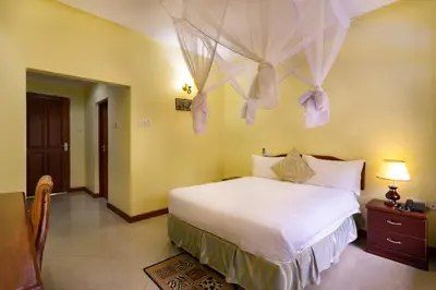 a bedroom with a bed with mosquito nets on the wall at Mvuli Hotels Arusha in Arusha