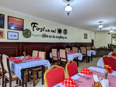 a restaurant with tables and chairs and a sign on the wall at Mvuli Hotels Arusha in Arusha