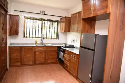 a kitchen with wooden cabinets and a stainless steel refrigerator at EMALI ARUSHA HOME in Arusha
