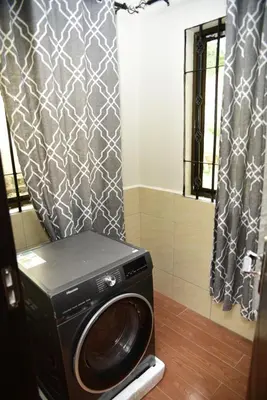 a washing machine in a bathroom with a shower curtain at EMALI ARUSHA HOME in Arusha