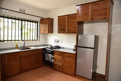 a kitchen with wooden cabinets and a stainless steel refrigerator at EMALI ARUSHA HOME in Arusha