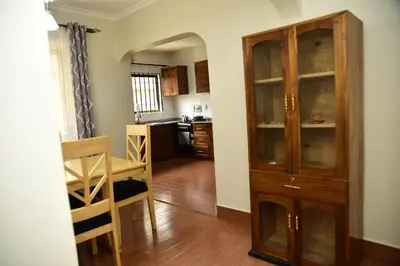 a living room with a wooden cabinet and a kitchen at EMALI ARUSHA HOME in Arusha