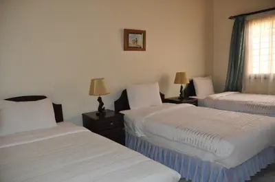 a room with two beds and two lamps and a window at The Milimani Lodge in Arusha