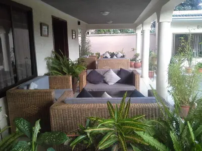 a patio with wicker chairs and a couch on a porch at The Milimani Lodge in Arusha