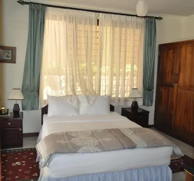 a bedroom with a bed and a large window at The Milimani Lodge in Arusha