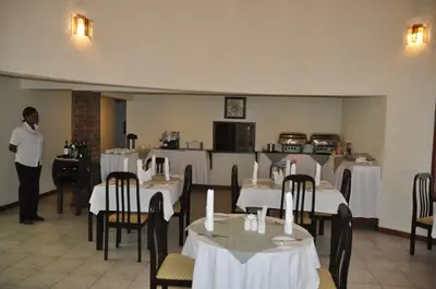 a woman standing in a dining room with tables at The Milimani Lodge in Arusha