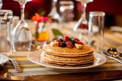 a stack of pancakes with fruit on a table at Tulia Boutique Hotel & Spa in Arusha