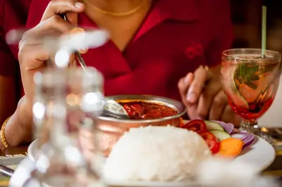 a woman sitting at a table with rice and a drink at Tulia Boutique Hotel & Spa in Arusha