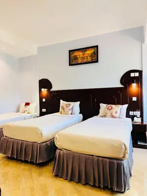 two beds in a room with white walls at Green Mountain Hotel in Arusha