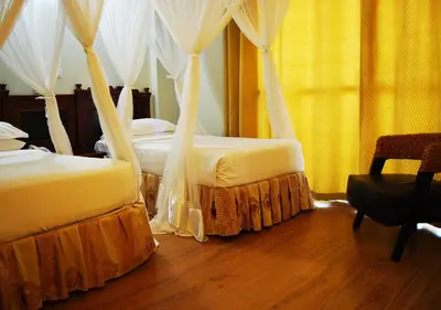 a bedroom with two beds with curtains and a chair at Mc-Elly's Hotel in Arusha