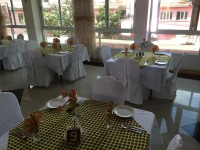 a dining room with white tables and white chairs at Mc-Elly's Hotel in Arusha