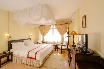 a bedroom with a bed and a desk and a television at New Safari Hotel in Arusha