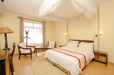 a bedroom with a large bed and a table and chairs at New Safari Hotel in Arusha