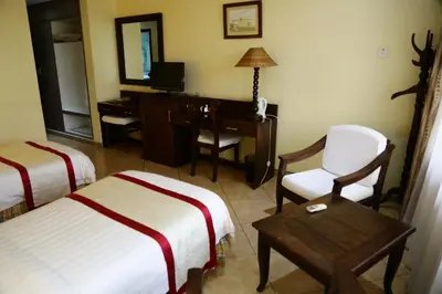 a hotel room with two beds and a desk and a chair at New Safari Hotel in Arusha
