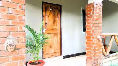 a house with a wooden door and a brick wall at Home Feeling Neneu Lodge in Moshi