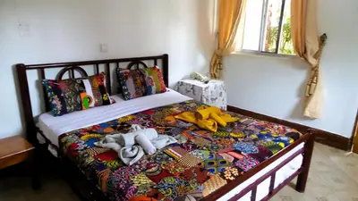 a bedroom with a bed covered in a colorful comforter at Home Feeling Neneu Lodge in Moshi