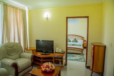 a living room with a tv and a chair and a mirror at Corridor Springs Hotel in Arusha